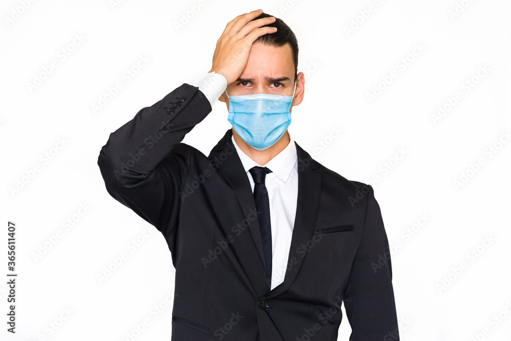 Worried businessman stressed with hand on face wearing a blue face mask and a suit. Isolated against a white background.
Worried businessman stressed with hand on face wearing a blue face mask and a suit. Isolated against a white background.