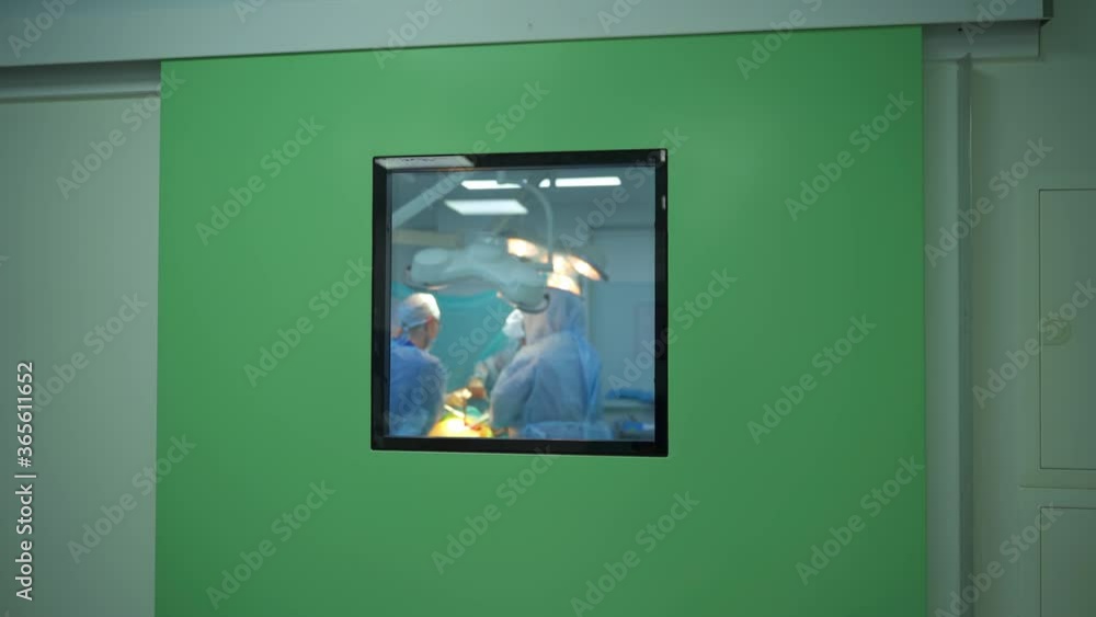 Operation in hospital. View through the window on surgical process with group of specialists. Medical concept. Operation in hospital. View through the window on surgical process with group of specialists. Medical concept.