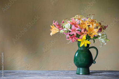 lily in ceramic green jug on background wall