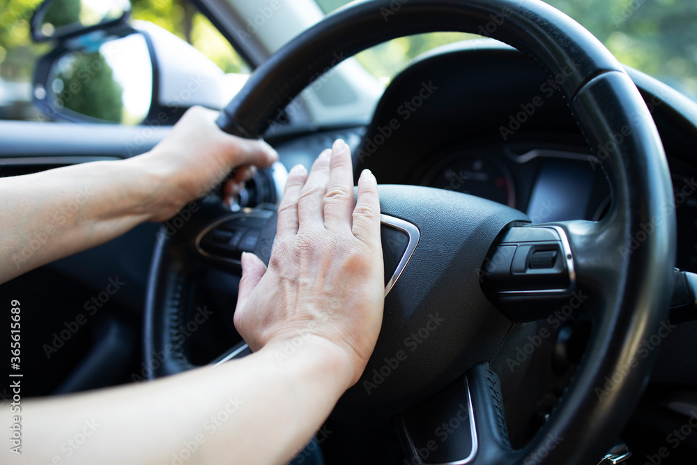 Close up view of car steering wheel and hand pressing horn or honk. Traffic jam and honking.