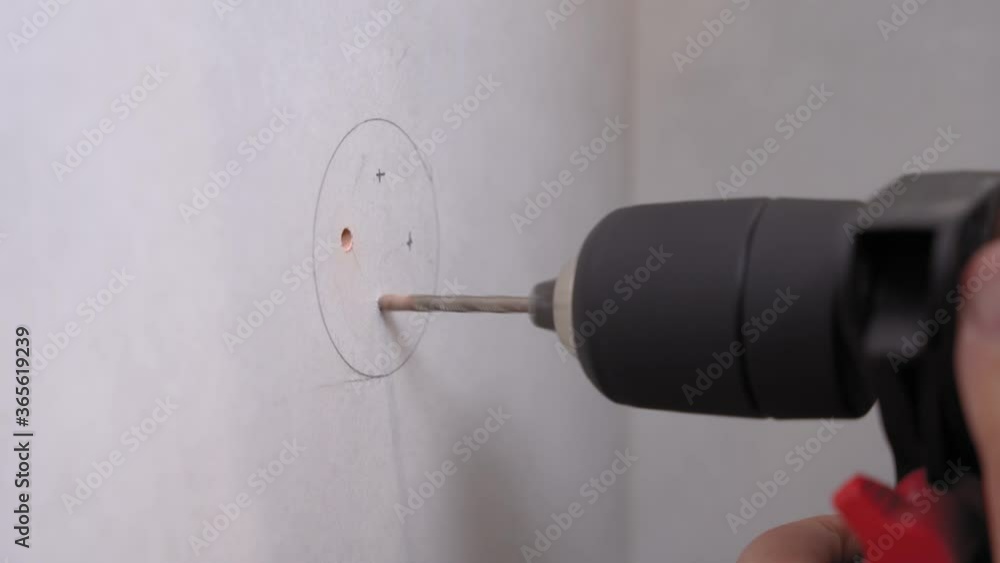 Husband or handyman drills holes in surface of wall according to a