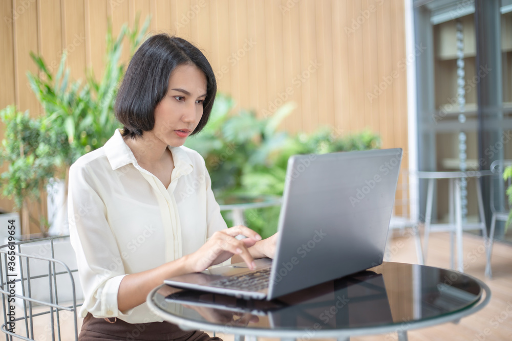 Young Asian woman using laptop computer and tablet PC to working in the modern co working space Young Asian woman using laptop computer and tablet PC to working in the modern co working space
