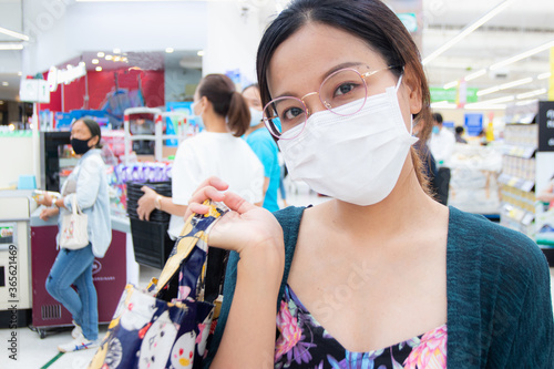 NONTHABURI, THAILAND - APRIL18, 2020: Beautiful Asean woman wearing the medical masks for shopping in the supermarket. photo