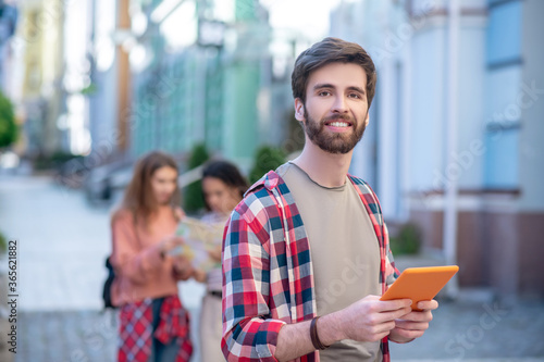 Satisfied guy with a tablet traveling around the city