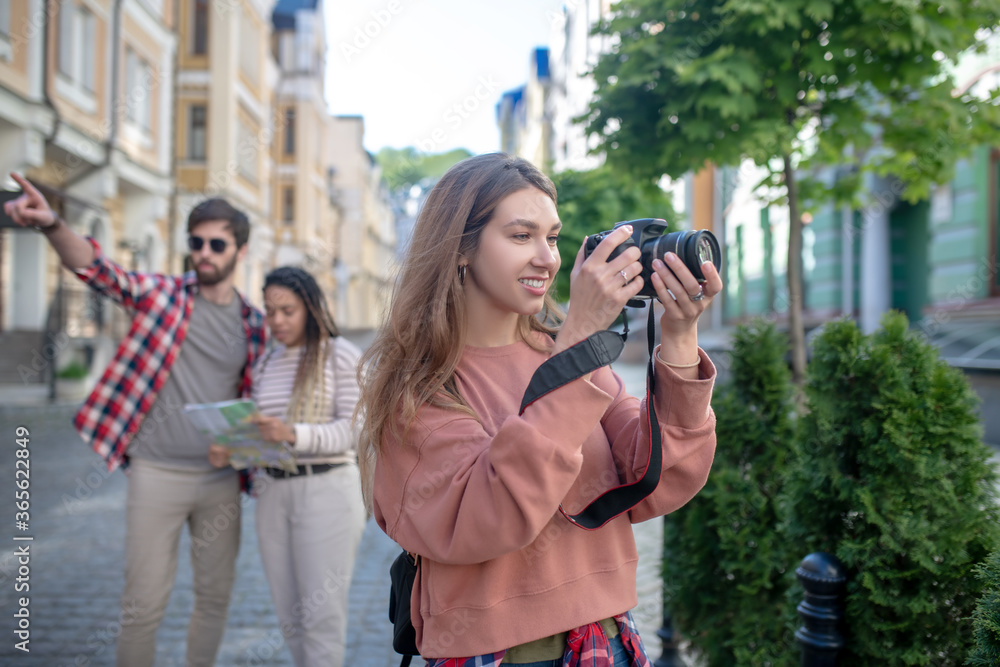 Girl looking at camera, guy with girlfriend with map at distance