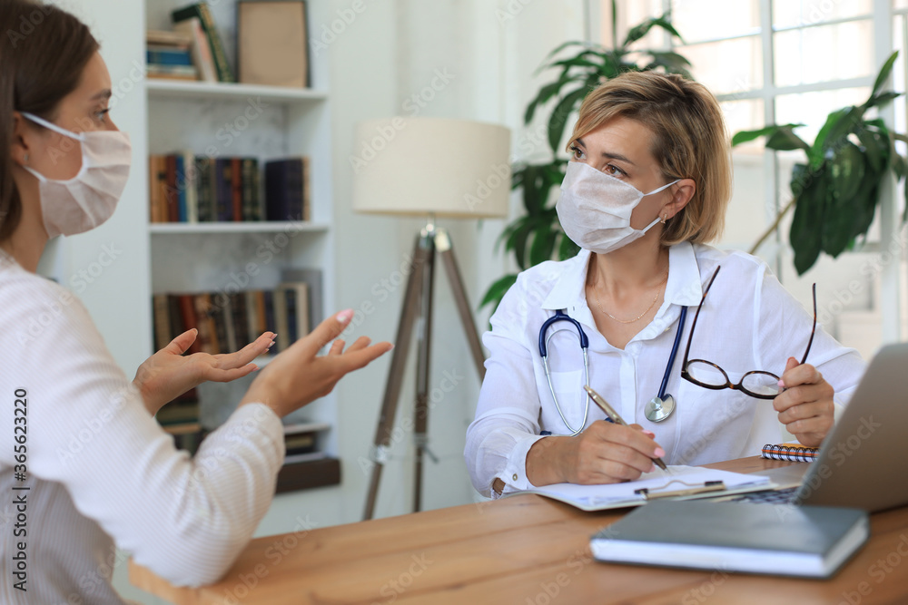 Middle aged female doctor therapist in medical mask on consultation with patient in office. Middle aged female doctor therapist in medical mask on consultation with patient in office.