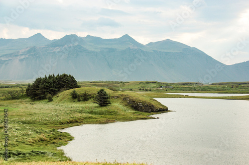 green lake shore, small mountains are on the horizon, nature of Iceland