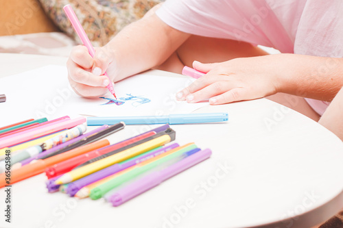 Favorite activity of the child. A happy family. The girl draws with colored markers. Girl's hands.