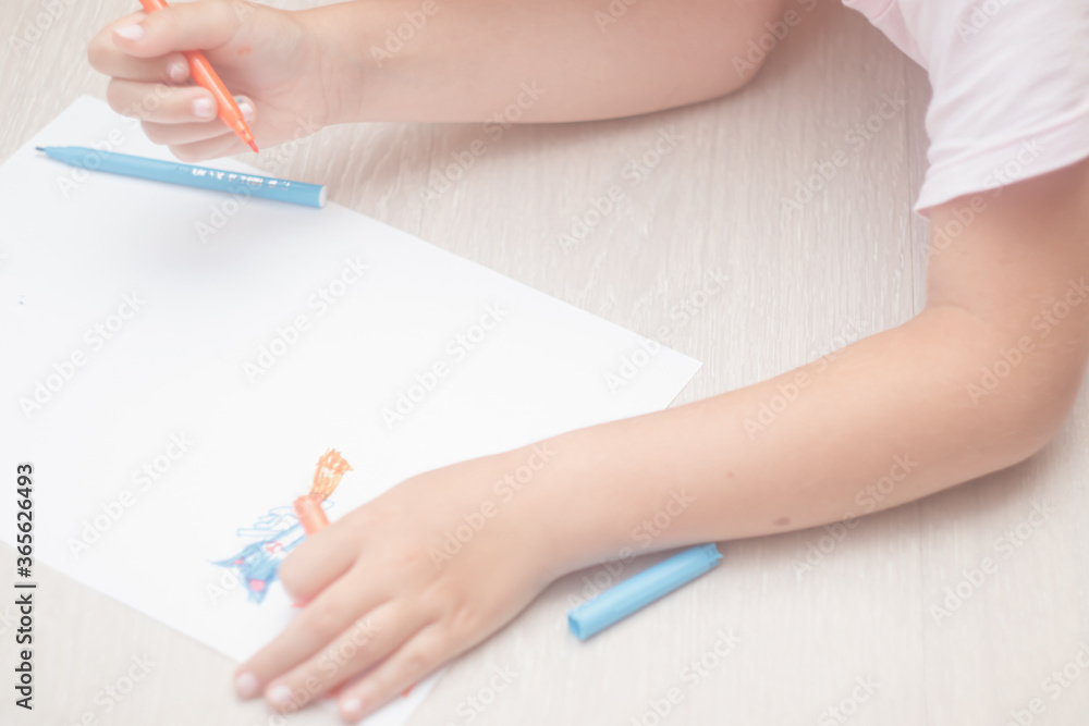 Fototapeta premium Favorite activity of the child. A happy family. The girl draws with colored markers. Girl's hands.