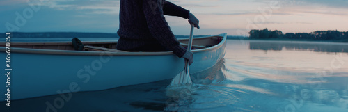 Fotografie CU view of a paddle, man canoeing alone boat on a large lake at dawn