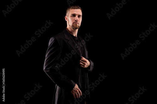 Portrait of a business man in black suit isolated on black background.