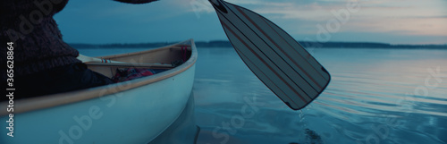 Fotografie CU view of a paddle, man canoeing alone boat on a large lake at dawn