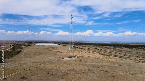 Telecommunication tower with sector antennas of a cellular operator and radio relay equipment in the steppe. Telecommunication equipment, antennas are designed for mobile phones. Clouds. photo