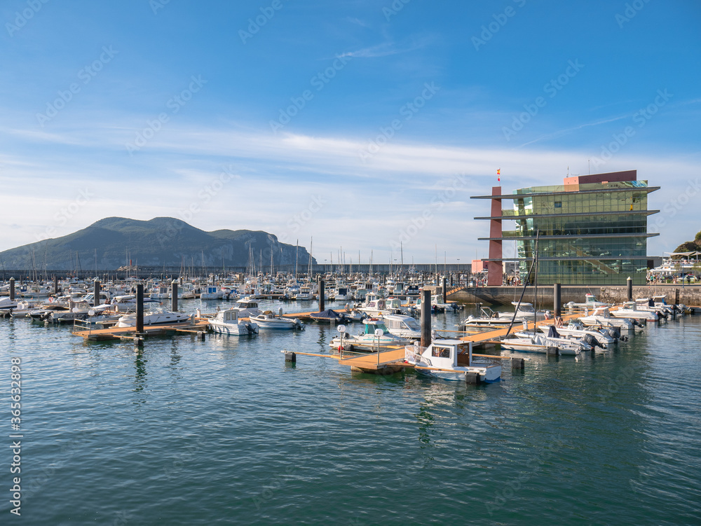 Modern Marina and marina building in Laredo with boats moored at the moorings and the Peña de Santoña in the background with a nice blue sky with clouds
