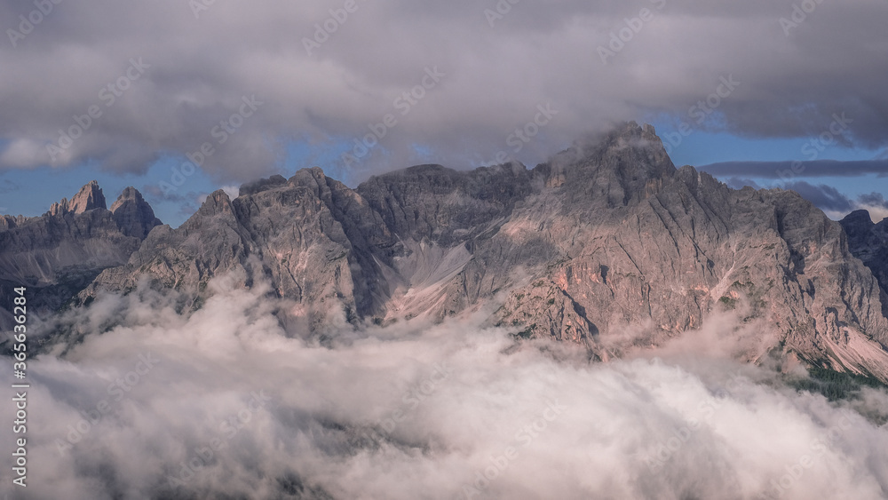 Unusual view of the Sesto Dolomites in Italy wrapped in clouds from top to bottom as seen from Carnic Peace Trail from Sillianer refuge to Obstansersee refuge on top of the Carnic Alps ridge, Austria.