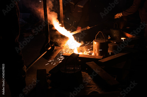Casting iron in a sand mold. Metal is heated until it becomes liquid and is then poured into a mold. The mold is a hollow cavity that includes the desired shape.