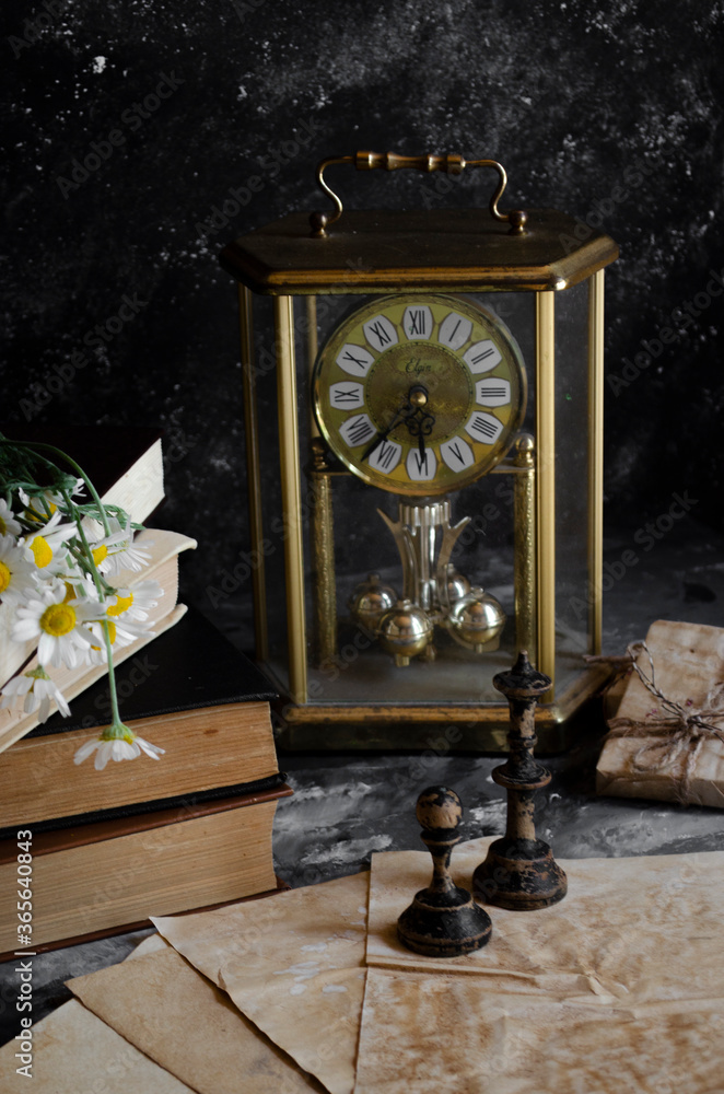 vintage clock on the table with books and chess