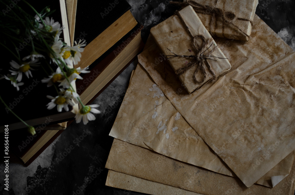 Obraz premium a stack of old books on the table with a bouquet of daisies