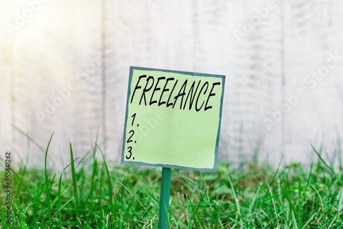 Conceptual hand writing showing Freelance. Concept meaning working at different firms rather than being permanently Plain paper attached to stick and placed in the grassy land photo