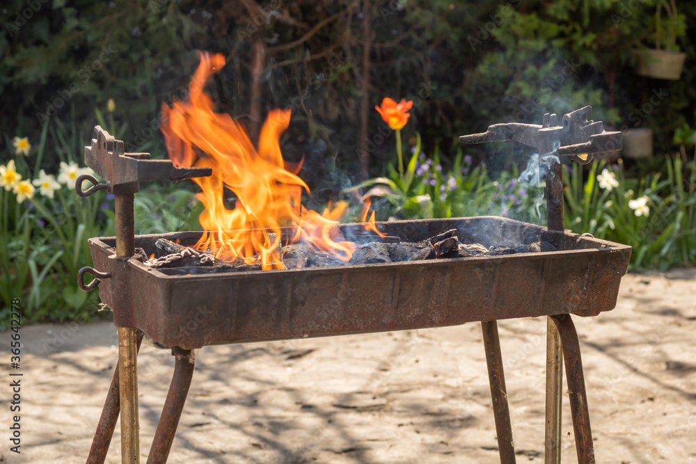 Making fire in a rustic barbecue grill with wood and charcoal, lot of flame and smoke