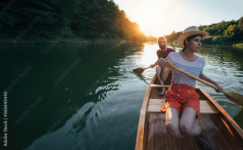 Woman and man canoeing on the sunset lake, copy space