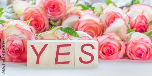 sign and text yes written on wooden blocks love and wedding concept bouquet of roses flowers background © Bonsales