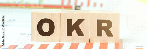 letters okr on wooden blocks on table with different graphs photo