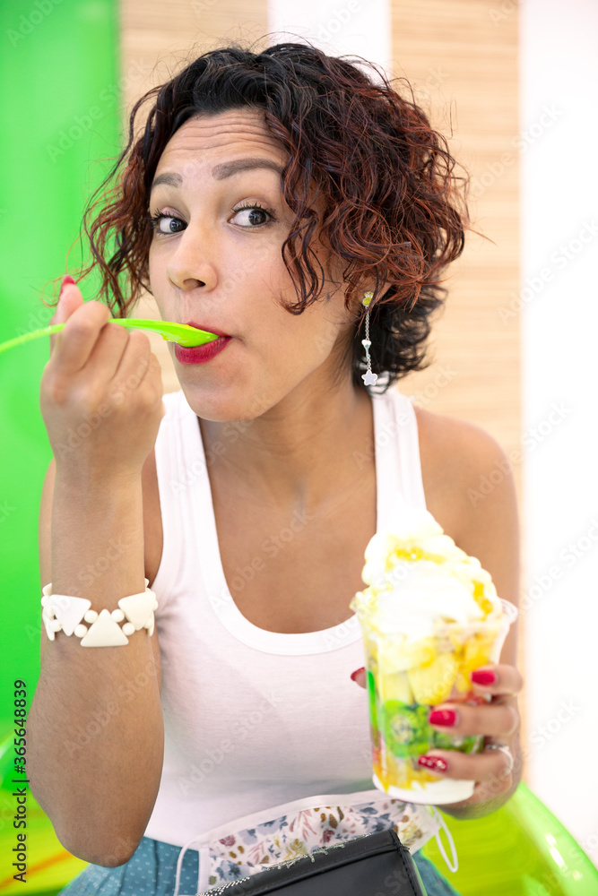 Portrait of a young, brown-skinned woman savoring an ice cream. Selective focus. Summer and healthy lifestyle concept. Portrait of a young, brown-skinned woman savoring an ice cream. Selective focus. Summer and healthy lifestyle concept.