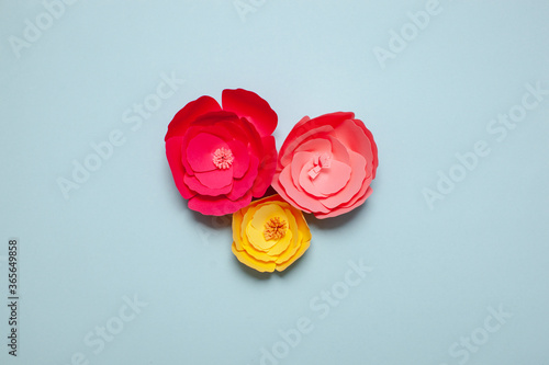 Paper art and craft handmade flowers. Pink and yellow colors. On blue background. photo