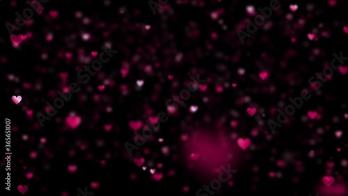Blurred pink hearts with shallow depth of field slowly rising on a black background.