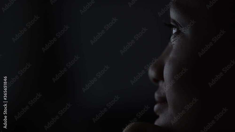 Static shot of young girl at night watching a screen whilst rubbing her nose and smiling, in slow motion Static shot of young girl at night watching a screen whilst rubbing her nose and smiling, in slow motion
