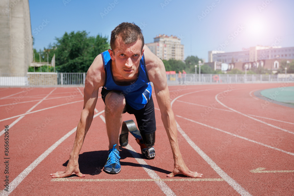Sportsman with prosthetic foot at the start of running track