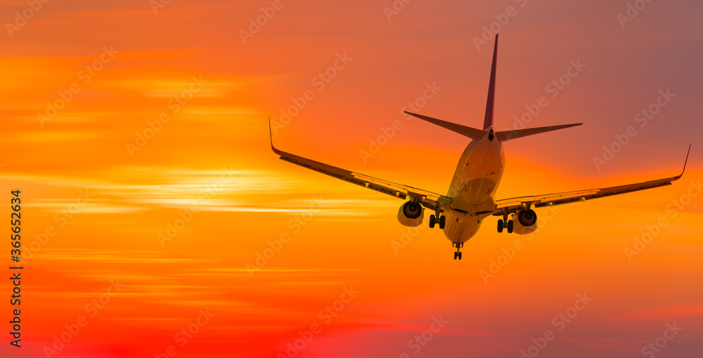 Airplane flying above tropical sea at sunset