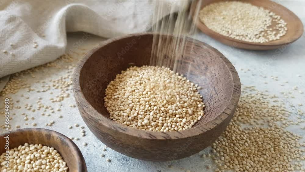 Pour Raw white Quinoa into A wooden bowl close up Pour Raw white Quinoa into A wooden bowl close up