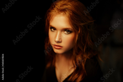 Black beauty close up portrait of red-haired redheaded woman with gorgeous beauty against black background in dramatic style. Classic woman portrait.
