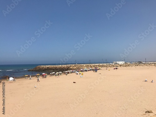 ASILAH / MOROCCO - August 04 2019 : People on a beach in Asilah, Morocco. Asilah is a fortified town on the northwest tip of the Atlantic coast of Morocco.  © MOUAD