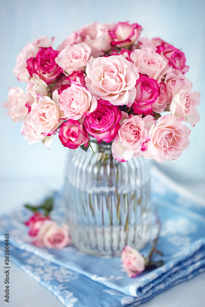 Delicate pink roses in a glass vase on the table.
Delicate pink roses in a glass vase on the table.