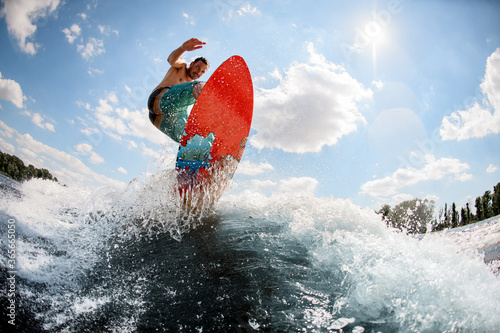 Canvas Print active man jumping on bright wakeboard down the river against the background of