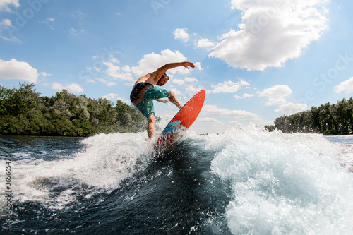 Active guy jumping on the waves of the river