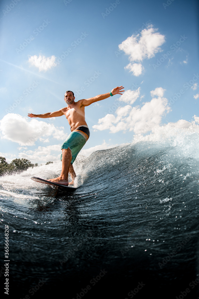 view of man on surfboard who is actively riding up the wave