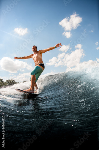 view of man on surfboard who is actively riding up the wave