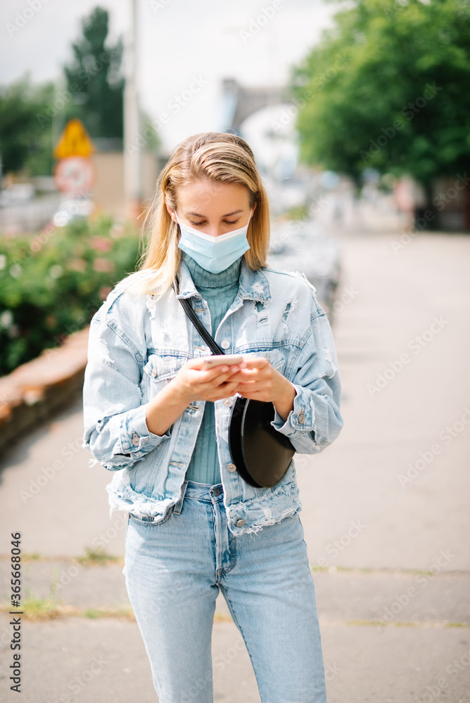 Young woman wearing antibacterial mask using phone in a city. Young woman wearing antibacterial mask using phone in a city.