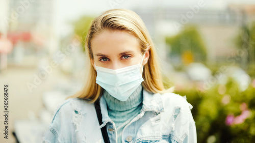 Portrait of young woman wearing antibacterial mask in a city.