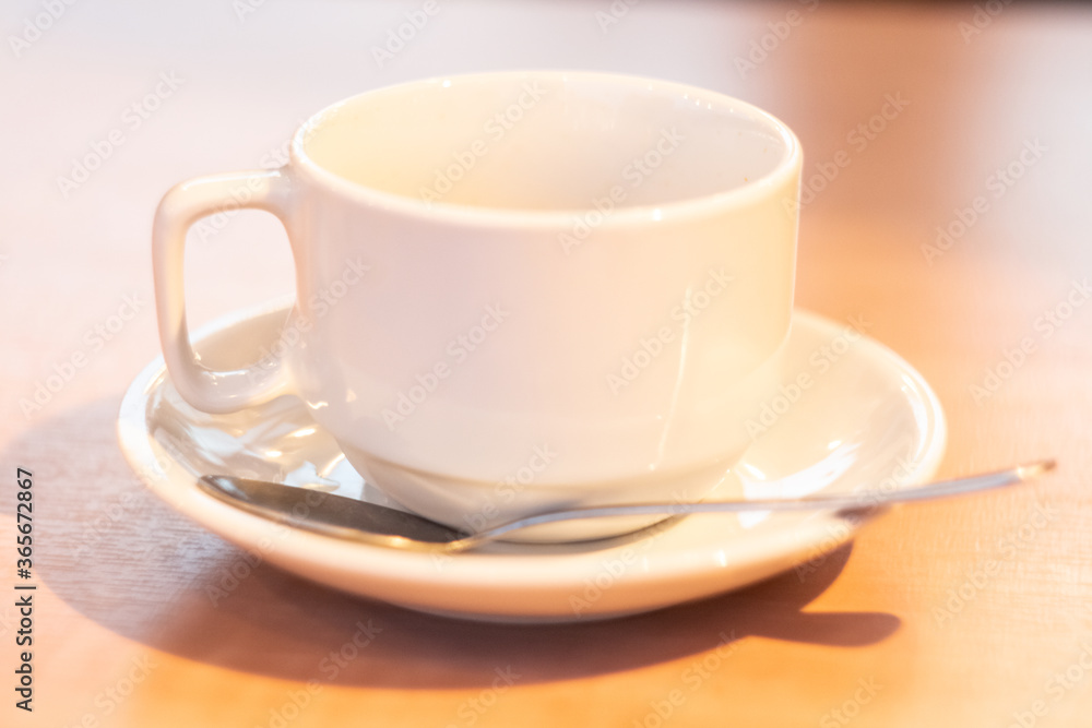 white mock up cup and saucer with spoon on wooden table close up white mock up cup and saucer with spoon on wooden table close up