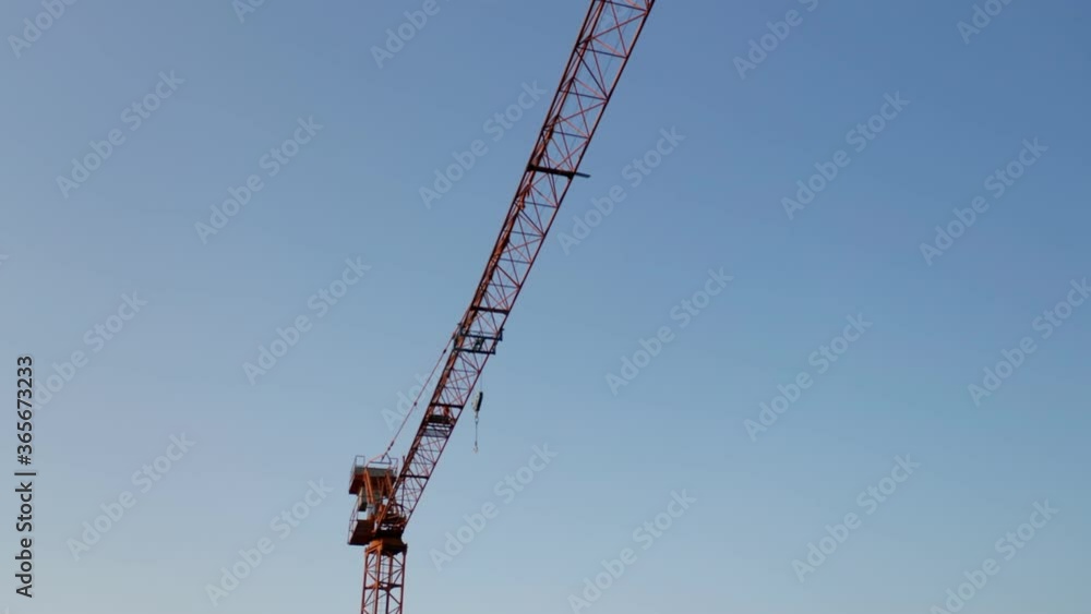 Close-up of an orange construction crane isolated on a blue sky Close-up of an orange construction crane isolated on a blue sky