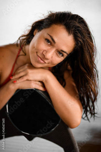 portrait of woman which leans her hands on surfboard and looks at camera