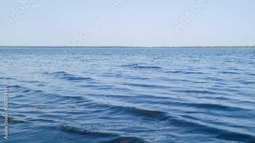 Light waves on the lake are illuminated by the evening rays of the sun. Blooming lake. Windy on a salt lake in Russia. Blue sky without clouds. Hot summer evening.