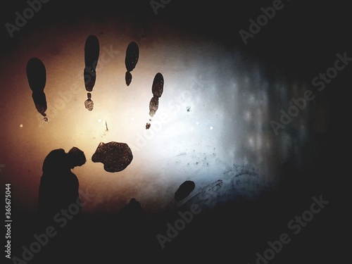Abstraction, handprint on cold or misted glass, in the dark. Mysterious fingerprint with the effect of mystery and mysticism. Cover for a detective story or unsolved mystery. Palm on glass.