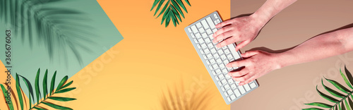 Person using a computer keyboard with tropical leaves and shadow