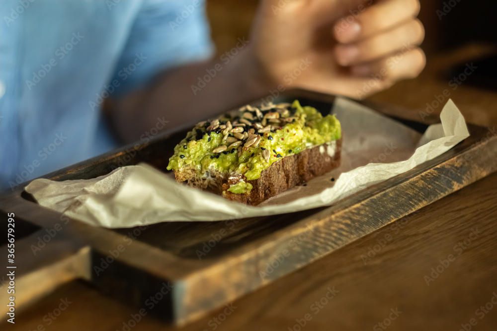 fresh bitten off guacamole sandwich with black sesame and sunflower seeds. rustic serving